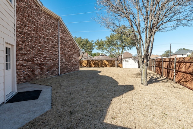 view of yard featuring a fenced backyard, a storage unit, and an outbuilding