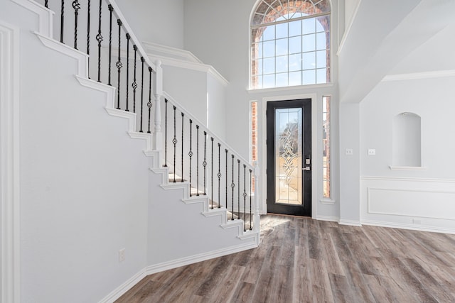 foyer featuring stairway, wood finished floors, a towering ceiling, and baseboards