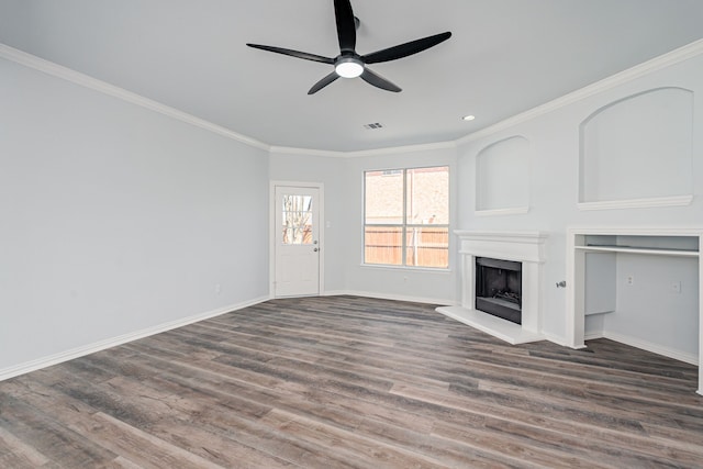 unfurnished living room featuring crown molding, a fireplace with raised hearth, visible vents, wood finished floors, and baseboards