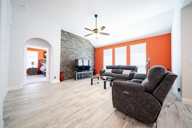 living room with vaulted ceiling, light wood-style floors, arched walkways, and ceiling fan