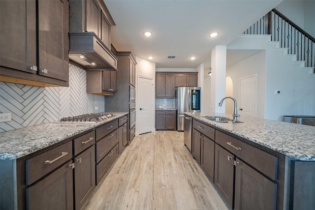 4130 Lagoon Pl, Royse City, TX 75189 - kitchen with a sink, appliances with stainless steel finishes, light wood finished floors, dark brown cabinetry, and tasteful backsplash