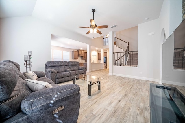 living room featuring vaulted ceiling, stairway, visible vents, and light wood-type flooring