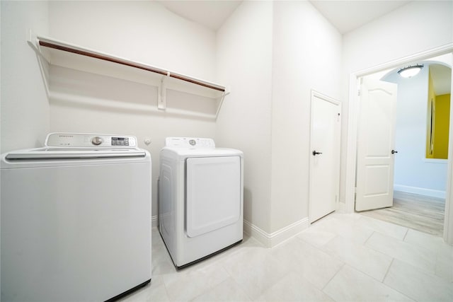 washroom featuring light tile patterned floors, baseboards, laundry area, and washing machine and clothes dryer