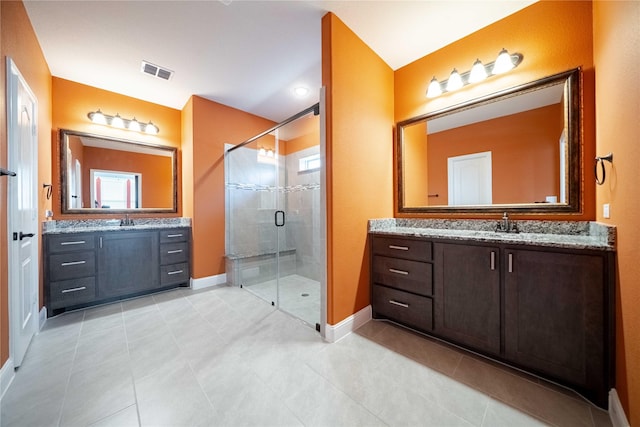 full bathroom featuring baseboards, visible vents, two vanities, a stall shower, and a sink