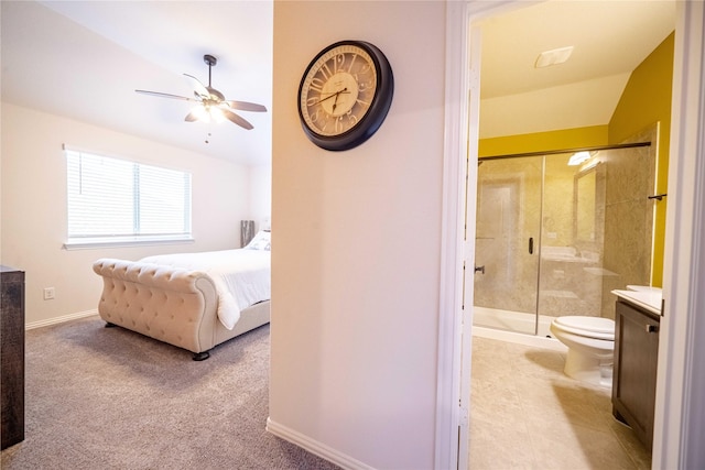 carpeted bedroom featuring lofted ceiling, a ceiling fan, ensuite bathroom, and baseboards