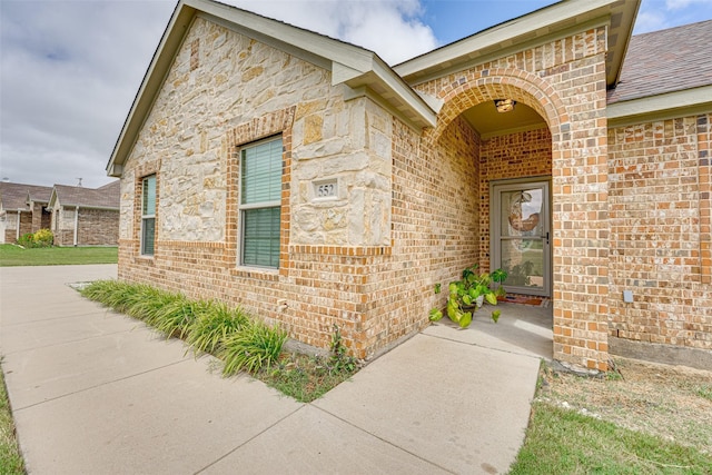 entrance to property featuring stone siding and brick siding