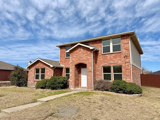 traditional-style house with brick siding, a front yard, and fence