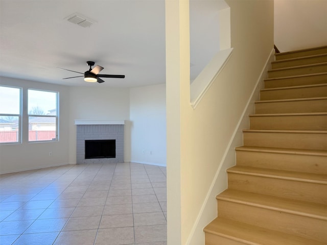 stairway with a fireplace, visible vents, a ceiling fan, tile patterned flooring, and baseboards