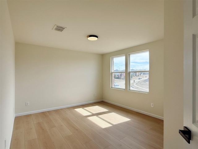 unfurnished room featuring light wood finished floors, baseboards, and visible vents