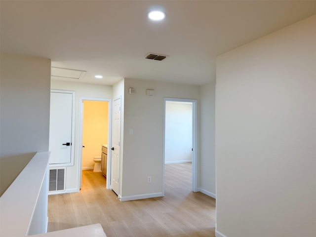 corridor featuring recessed lighting, visible vents, light wood-style flooring, and an upstairs landing