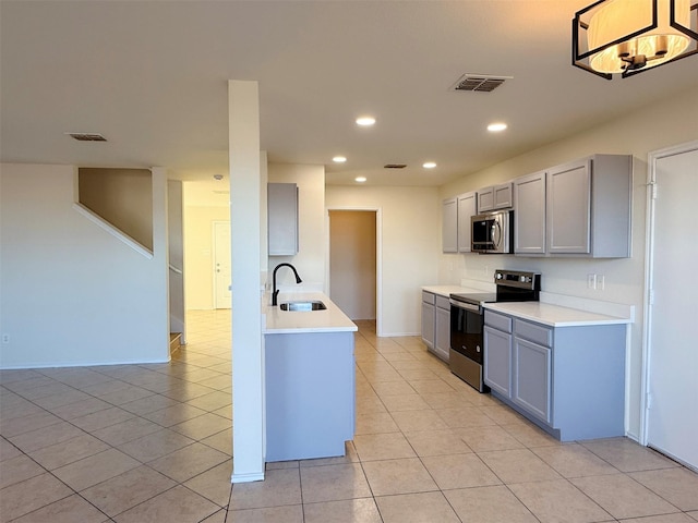 kitchen with appliances with stainless steel finishes, gray cabinets, visible vents, and a sink