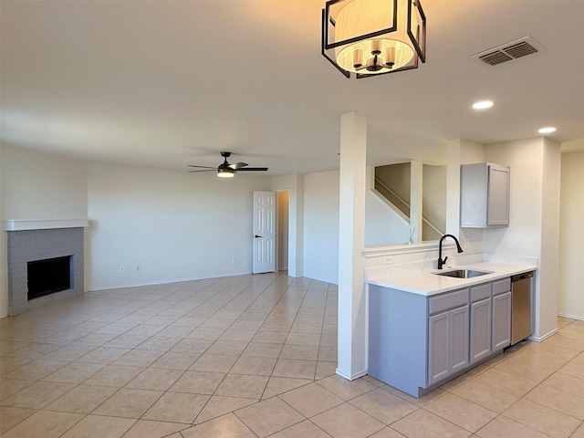 kitchen with a fireplace, gray cabinets, light countertops, visible vents, and a sink