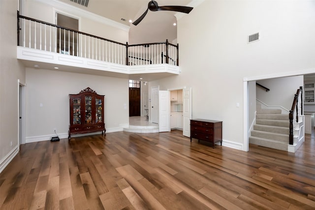 unfurnished living room featuring baseboards, visible vents, a ceiling fan, wood finished floors, and stairs