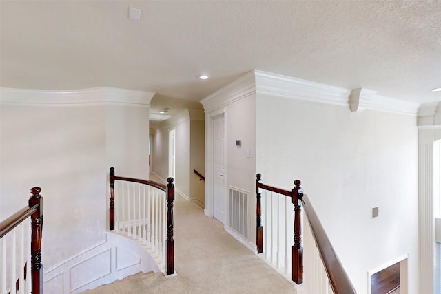 corridor featuring crown molding, visible vents, light carpet, a textured ceiling, and an upstairs landing