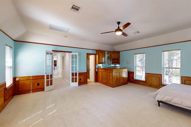 unfurnished bedroom with light colored carpet, french doors, a wainscoted wall, and visible vents