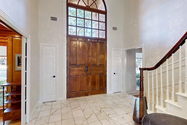 entrance foyer featuring a high ceiling, marble finish floor, stairway, and visible vents