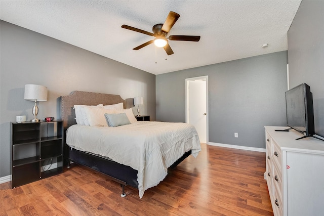 bedroom with a textured ceiling, wood finished floors, and baseboards