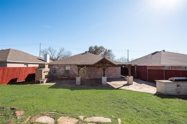 back of house featuring brick siding, a yard, a patio, a shingled roof, and a fenced backyard