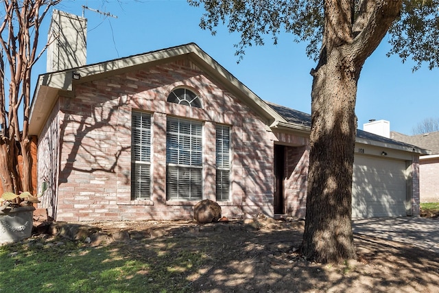 view of side of property featuring a garage, a chimney, and brick siding