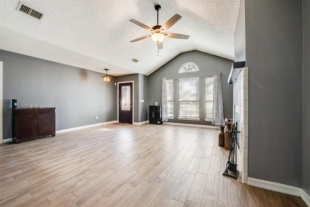 unfurnished living room with lofted ceiling, visible vents, light wood-style floors, a ceiling fan, and baseboards