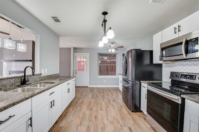 kitchen featuring stone countertops, a sink, visible vents, appliances with stainless steel finishes, and light wood-type flooring