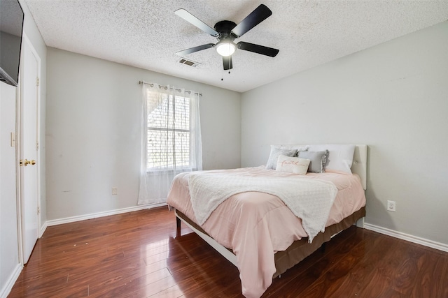 bedroom with a ceiling fan, a textured ceiling, baseboards, and wood finished floors