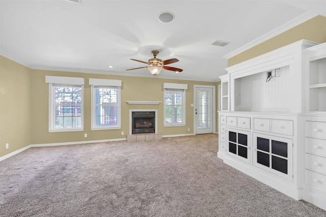 unfurnished living room with crown molding, a fireplace, visible vents, carpet flooring, and ceiling fan