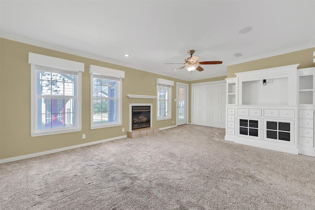 unfurnished living room with carpet floors, a fireplace with raised hearth, ornamental molding, ceiling fan, and baseboards