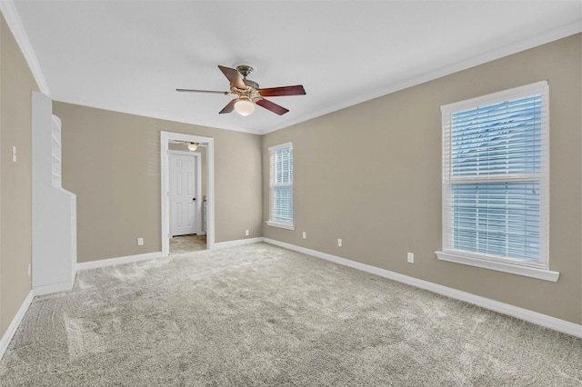 carpeted empty room with ceiling fan, ornamental molding, and baseboards