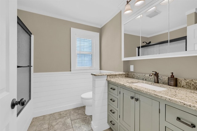 bathroom featuring wainscoting, crown molding, vanity, and toilet