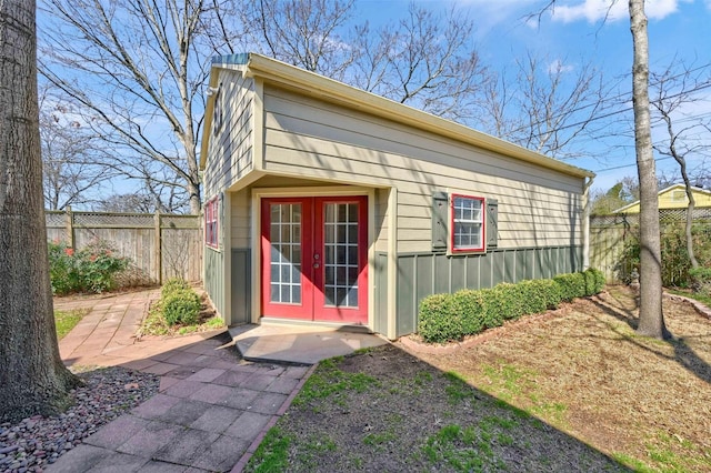 view of outbuilding featuring french doors, fence, and an outdoor structure