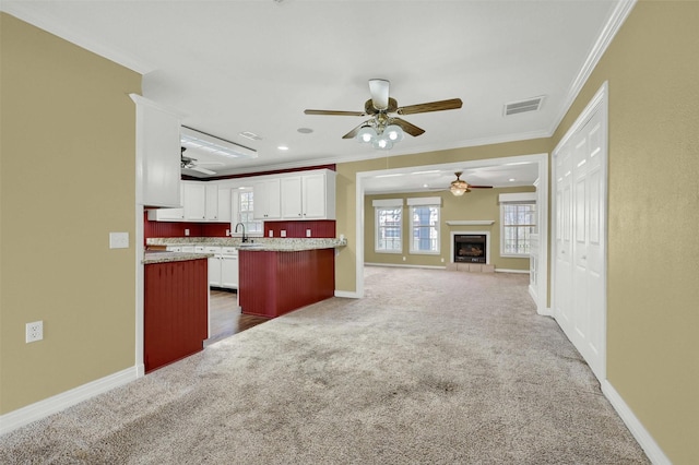 kitchen featuring visible vents, white cabinets, open floor plan, dark colored carpet, and crown molding