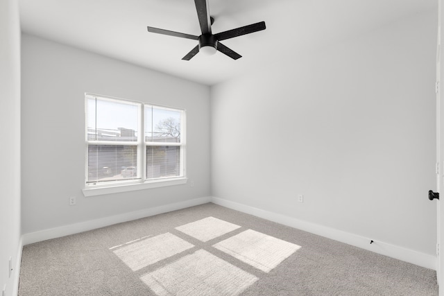 carpeted spare room with a ceiling fan and baseboards