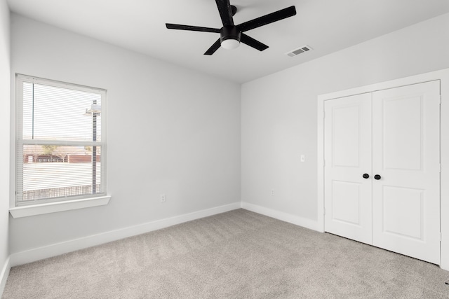 unfurnished bedroom featuring baseboards, visible vents, ceiling fan, carpet floors, and a closet