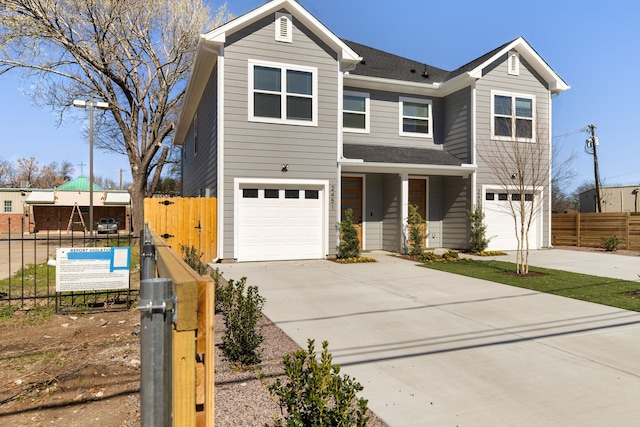 traditional home with an attached garage, fence, and concrete driveway