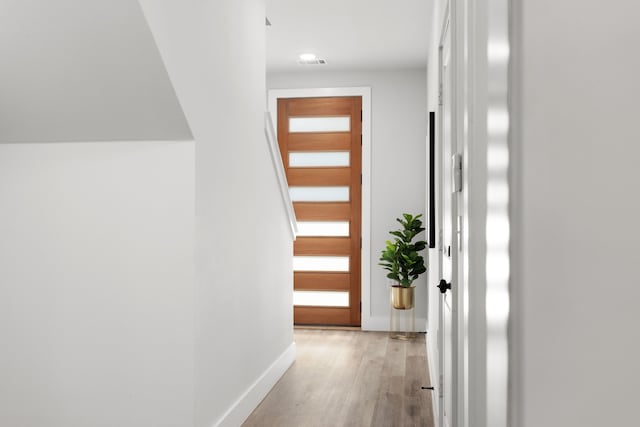 corridor featuring light wood-style flooring, visible vents, and baseboards