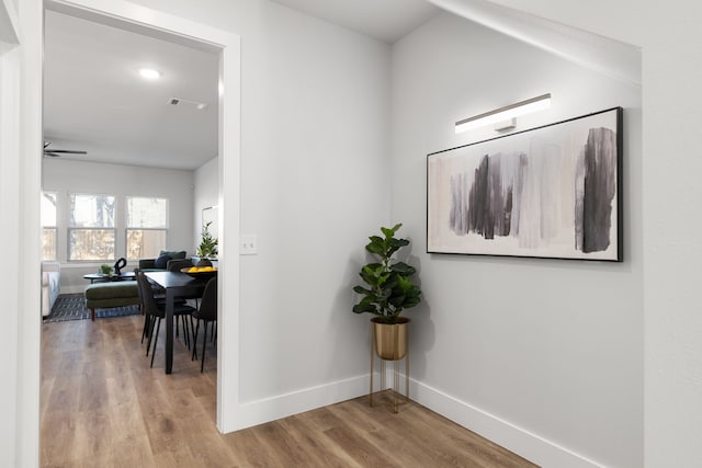 hall featuring visible vents, baseboards, and wood finished floors