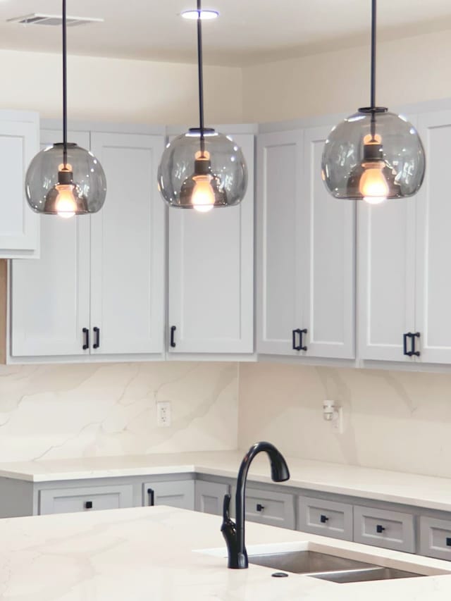 5147 Chapman St, Fort Worth, TX 76105 - kitchen featuring decorative light fixtures, decorative backsplash, light stone counters, and a sink