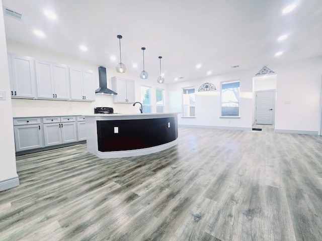 kitchen featuring open floor plan, wall chimney exhaust hood, visible vents, and light wood-type flooring