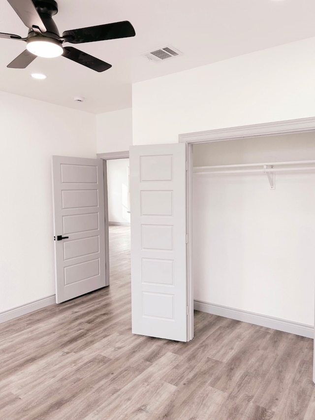 unfurnished bedroom featuring light wood-style flooring, baseboards, visible vents, and a closet