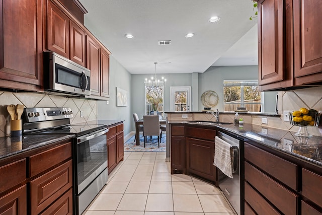 kitchen featuring light tile patterned floors, visible vents, a peninsula, stainless steel appliances, and a sink