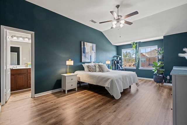 bedroom with visible vents, baseboards, ensuite bath, vaulted ceiling, and light wood-type flooring