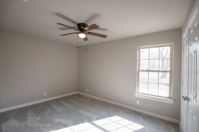 carpeted empty room featuring a healthy amount of sunlight, ceiling fan, and baseboards