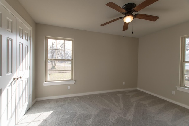 empty room featuring baseboards, a ceiling fan, and light colored carpet