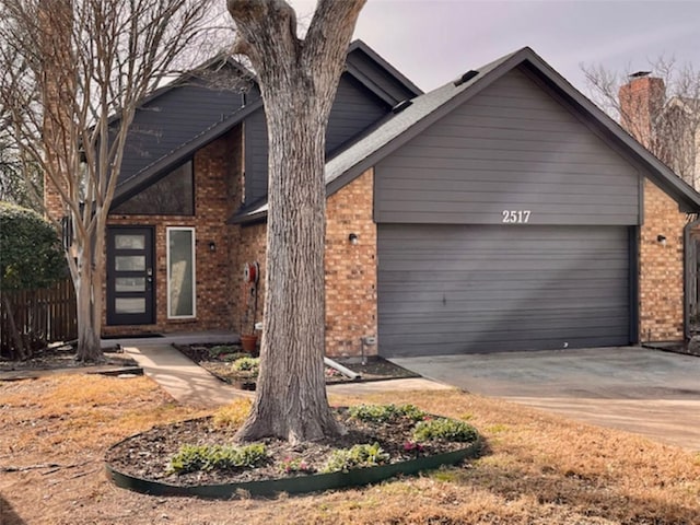 view of front of property featuring an attached garage, driveway, fence, and brick siding