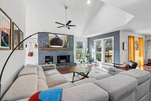 living room with ceiling fan, a fireplace, high vaulted ceiling, and wood finished floors