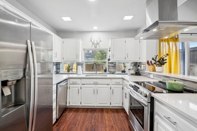 kitchen featuring a sink, appliances with stainless steel finishes, wall chimney range hood, backsplash, and dark wood finished floors