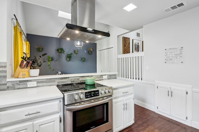 kitchen with visible vents, island range hood, stainless steel electric range, light countertops, and white cabinetry