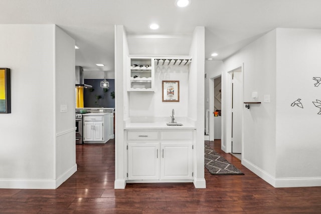 hallway featuring baseboards, a sink, dark wood finished floors, and recessed lighting