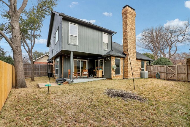 rear view of house featuring a yard, a chimney, central AC unit, a patio area, and a fenced backyard